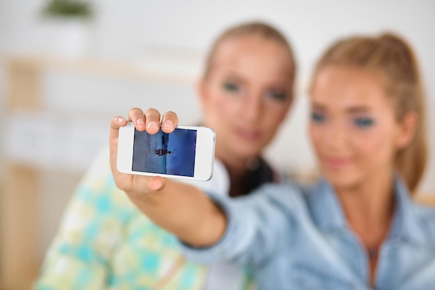 Due ragazze che scattano foto al telefono a casa