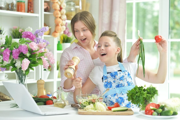Due ragazze che si divertono mentre preparano insalata fresca