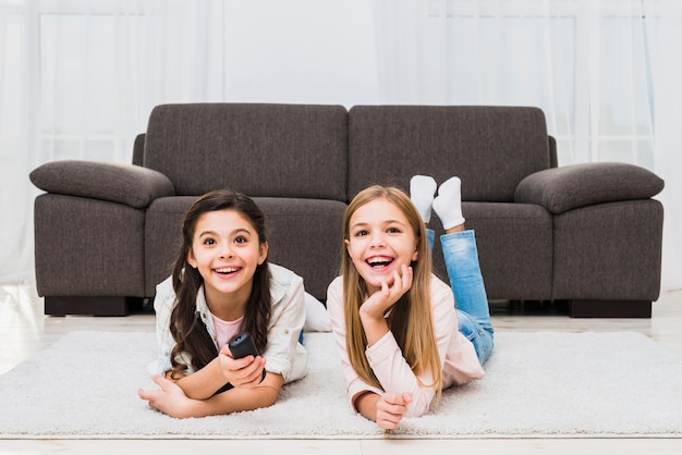 Due ragazze che si trovano sul tappeto godendo guardando la televisione