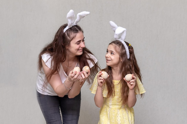 Due ragazze con le orecchie di coniglio di Pasqua stanno tenendo le uova di Pasqua nelle loro mani Buona Pasqua