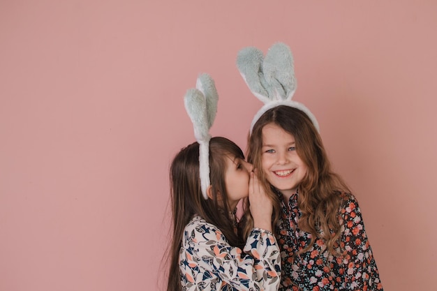 Due ragazze con orecchie da coniglio che tengono un cesto di uova di Pasqua