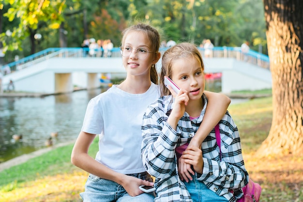 Due ragazze con telefoni a pulsante si rilassano in un parco estivo