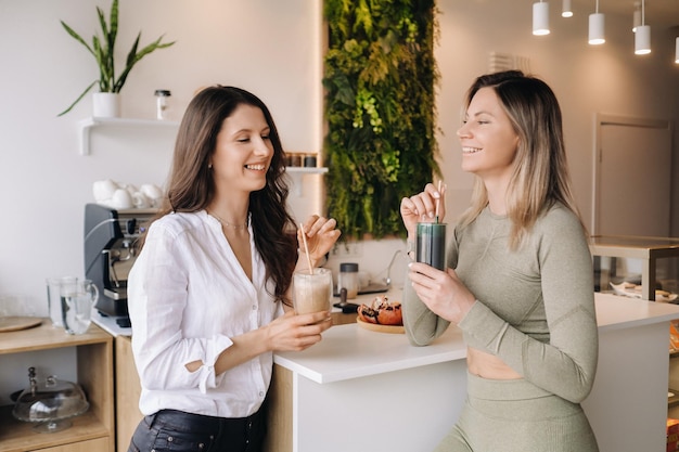 Due ragazze dall'aspetto sportivo con un cocktail in mano discutono di un'alimentazione sana e di una dieta