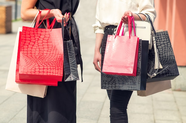 Due ragazze dopo lo shopping con le borse in mano.