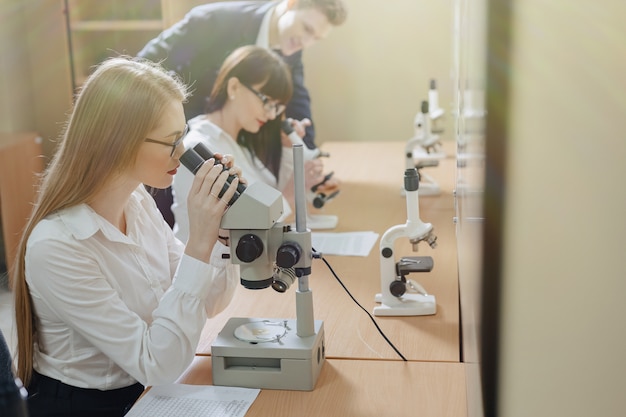 Due ragazze e un ragazzo lavorano con i microscopi