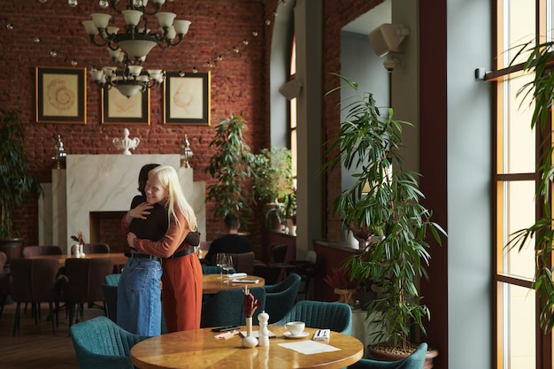 Due ragazze felici e affettuose che si abbracciano nella caffetteria