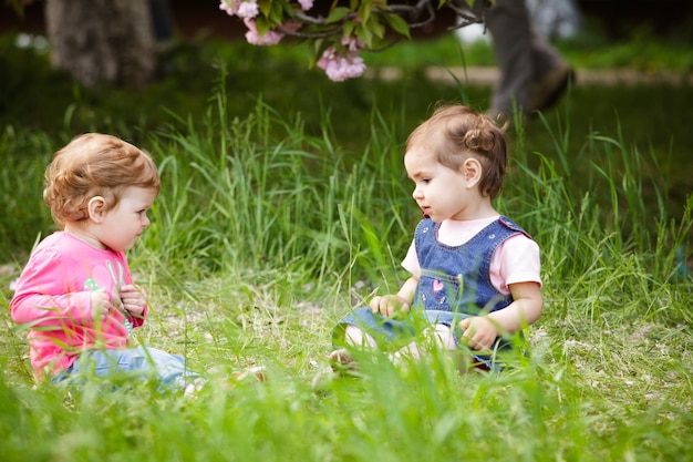 Due ragazze giocano in giardino, sedute sull'erba