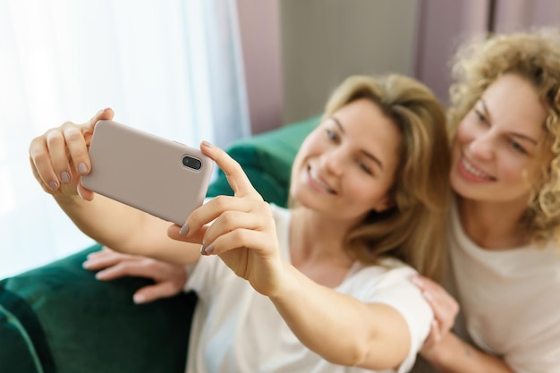 Due ragazze giovani e allegre che si fanno selfie insieme a casa