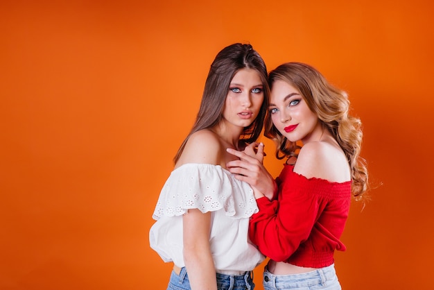 Due ragazze giovani e belle mostra emozioni e sorrisi in Studio su un'arancia