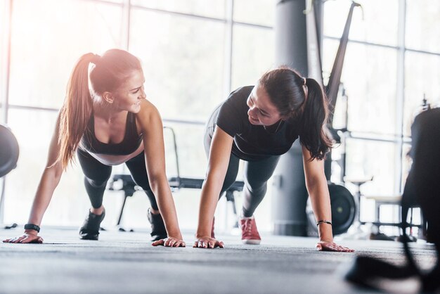 Due ragazze in abiti sportivi sono in palestra a fare esercizi insieme.