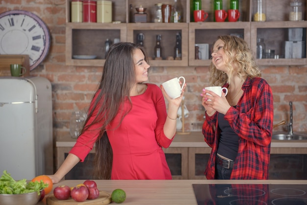 Due ragazze in chat con una tazza di caffè in cucina