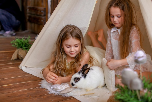 due ragazze in una tenda wigwam con un coniglio, tema pasquale