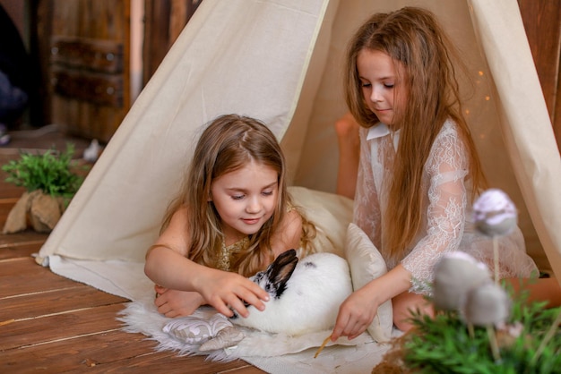 due ragazze in una tenda wigwam con un coniglio, tema pasquale