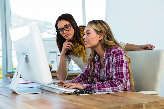 Due ragazze lavorano in ufficio su computer e tablet