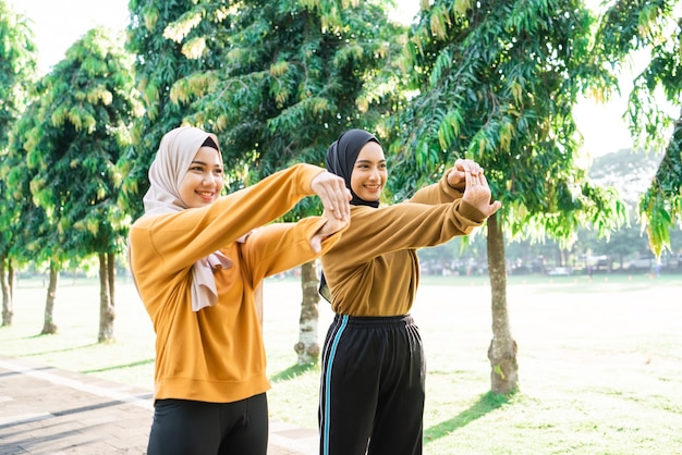 Due ragazze musulmane velate allungano le mani prima di fare jogging e fare sport all'aria aperta nel parco