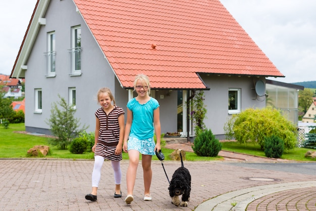 Due ragazze o bambini che camminano con il cane