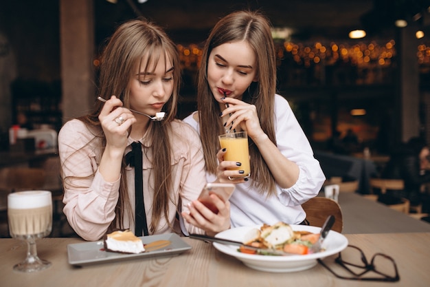 Due ragazze pranzando in un caffè con il telefono