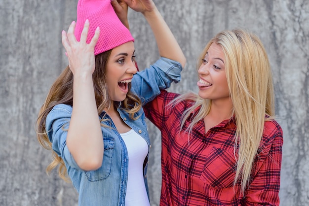 Due ragazze ridendo isolato sfondo grigio muro