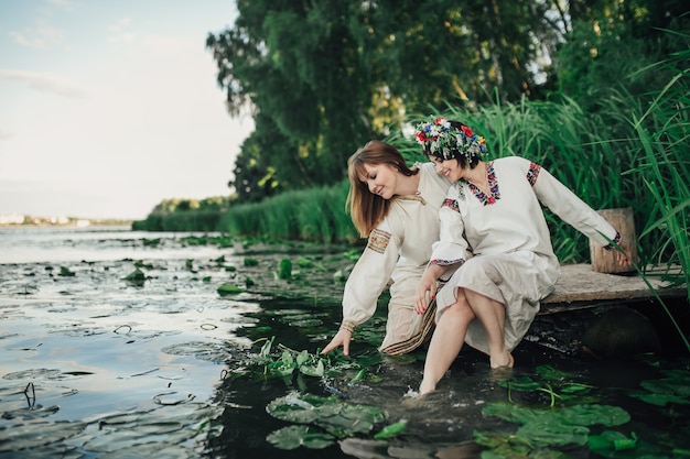 due ragazze sedute vicino all&#39;acqua