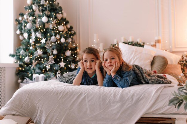 Due ragazze sono sdraiate sul letto all'interno della camera da letto di Natale. la vigilia della vacanza