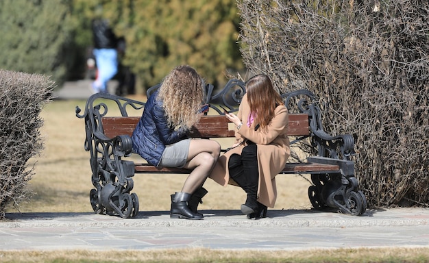 due ragazze sono sedute su una panchina