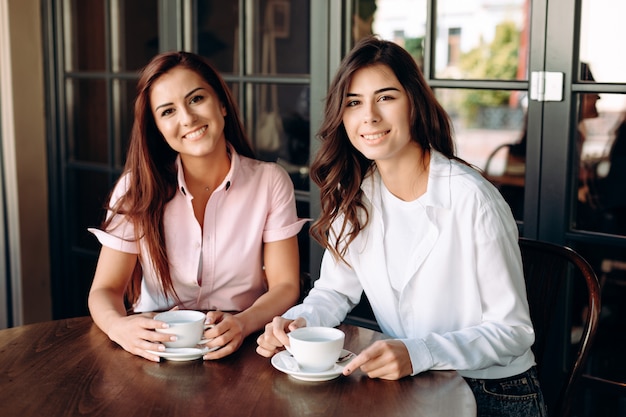 Due ragazze sorridenti di affari che bevono tè durante il pranzo di lavoro