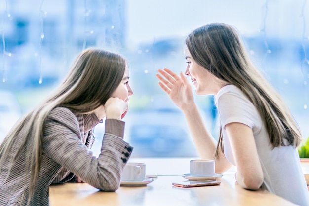 Due ragazze stanno bevendo il caffè nella caffetteria