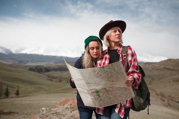 Due ragazze viaggiatrici con una mappa in piedi su una roccia in montagna