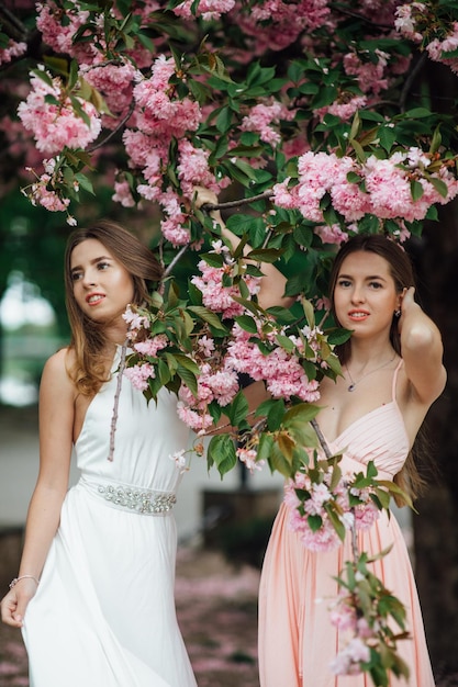 Due ragazze vicino a un albero in fiore. Ad esempio, un ritratto di una giovane bella donna alla moda