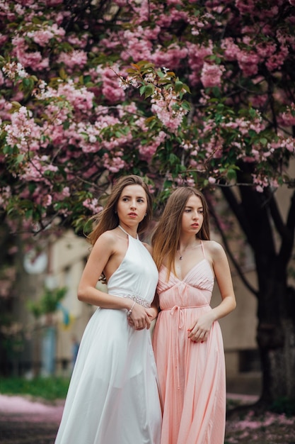 Due ragazze vicino a un albero in fiore. Ad esempio, un ritratto di una giovane bella donna alla moda