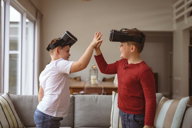 Due ragazzi caucasici che indossano cuffie vr si danno il cinque a casa