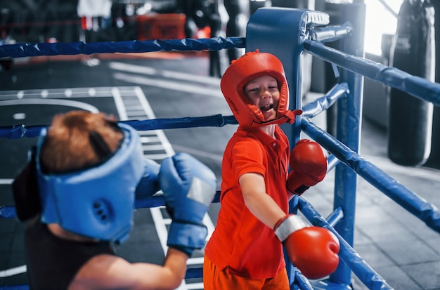 Due ragazzi in equipaggiamento protettivo hanno sparring e combattimenti sul ring.