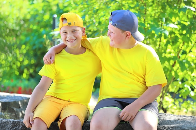 Due ragazzi in magliette gialle che si abbracciano seduti nel parco. Foto di alta qualità