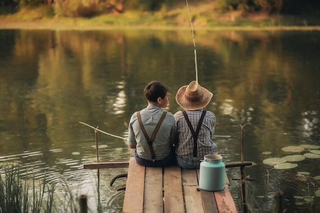 Due ragazzi stanno pescando sul lago del villaggio al tramonto in estate