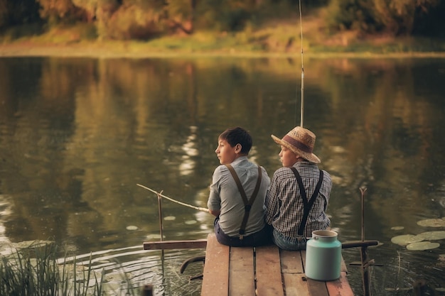 Due ragazzi stanno pescando sul lago del villaggio al tramonto in estate