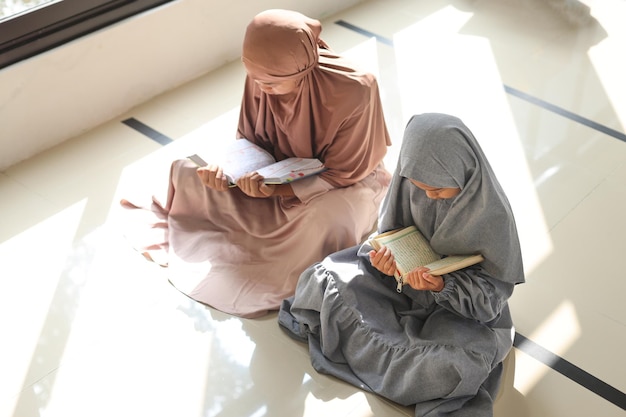 Due ragazzine musulmane che leggono il Corano vicino alla finestra della moschea