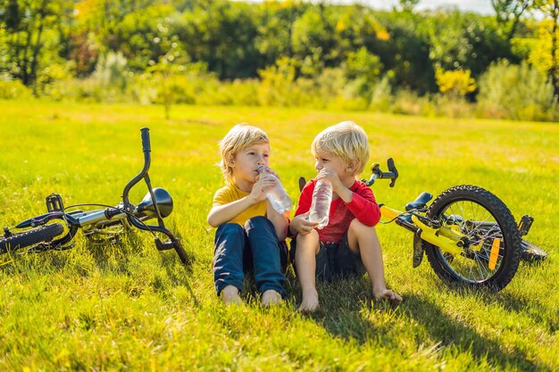 Due ragazzini bevono acqua nel parco dopo essere andati in bicicletta.