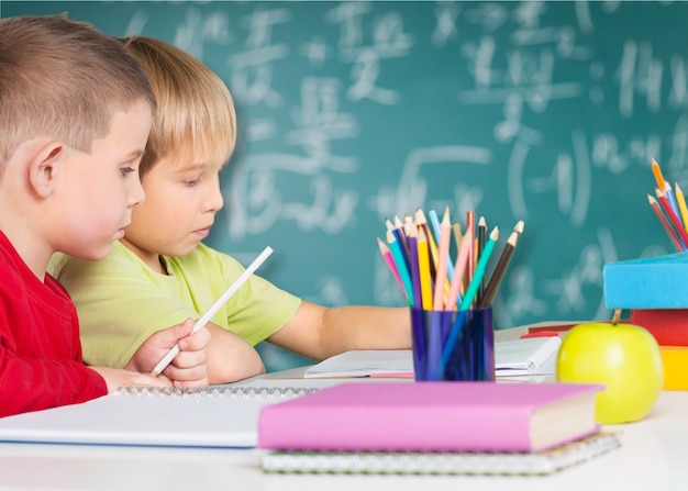 Due ragazzini che studiano matematica in classe con lavagna verde sullo sfondo