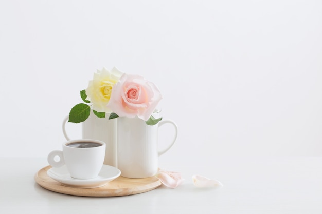 Due rose in tazze con una tazza di caffè