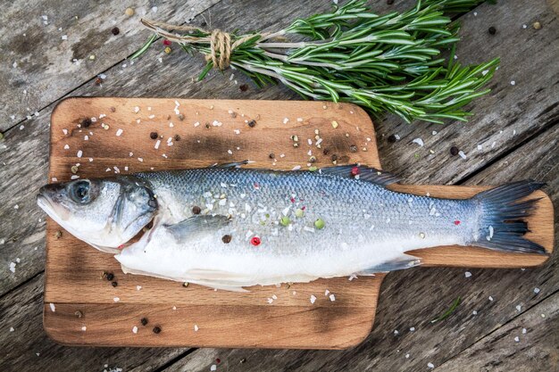 Due rosmarino crudo di branzino sullo sfondo di legno