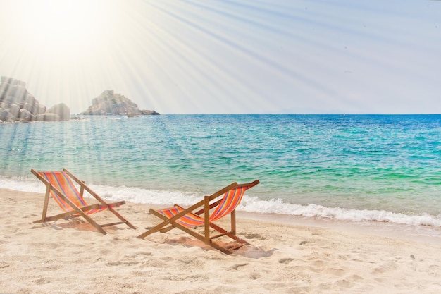 Due sedie a sdraio sulla spiaggia della baia con rocce sullo sfondo