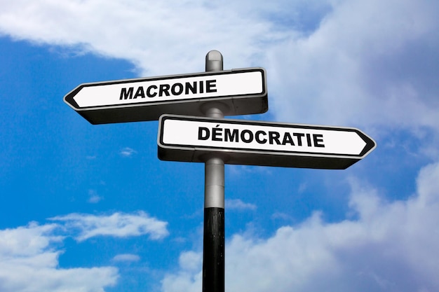 Due segnali di direzione uno che punta in modi opposti dicendo Macronie e Democratie