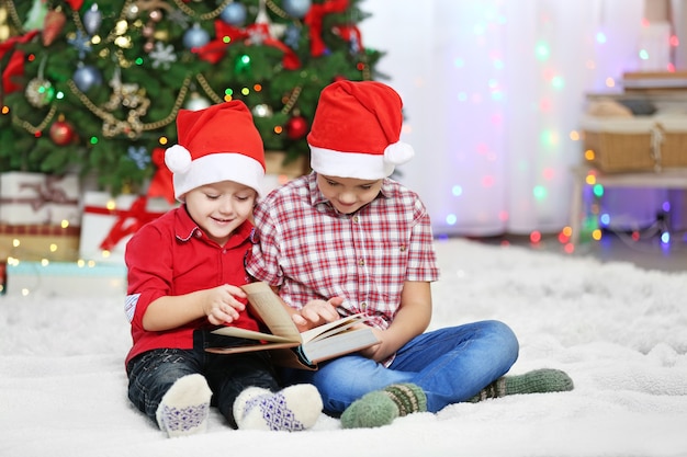 Due simpatici fratellini che leggono un libro sulla superficie della decorazione natalizia