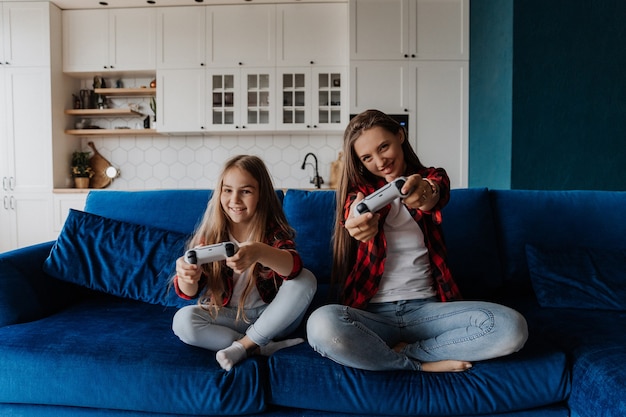 Due sorelle a casa si divertono e giocano a una console con un joystick