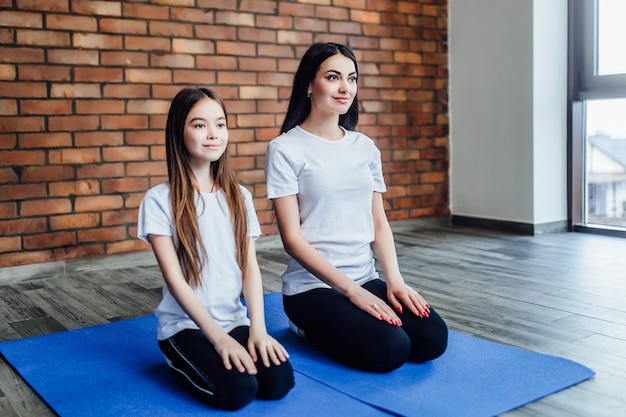 Due sorelle adorabili che praticano yoga insieme nel centro yoga.