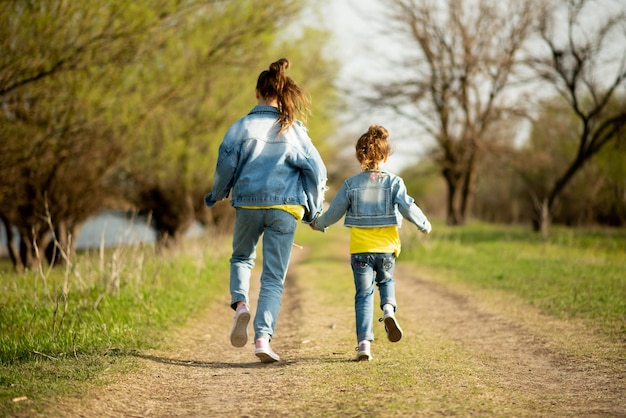 Due sorelle carine stanno correndo lungo una strada di campagna vuota Famiglia d'infanzia di libertà di primavera