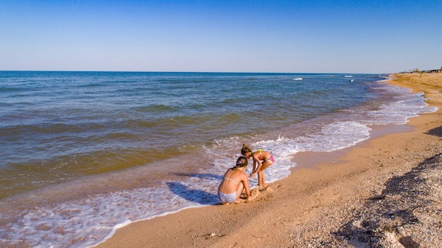 Due sorelle che giocano con la sabbia sulla costa del mare