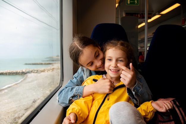 Due sorelle guardano fuori dal finestrino di un treno al mare Viaggio Vacanza Estate Vacanza in famiglia