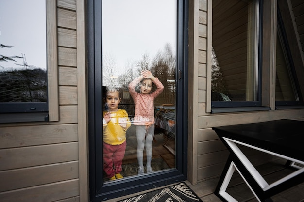 Due sorelle guardano la porta a vetri sulla terrazza di una piccola casa di campagna in legno