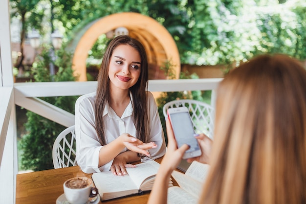 Due sorelle imparano nel caffè e parlano.